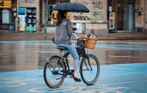 Big Picture: woman cycling whilst holding an umbrella